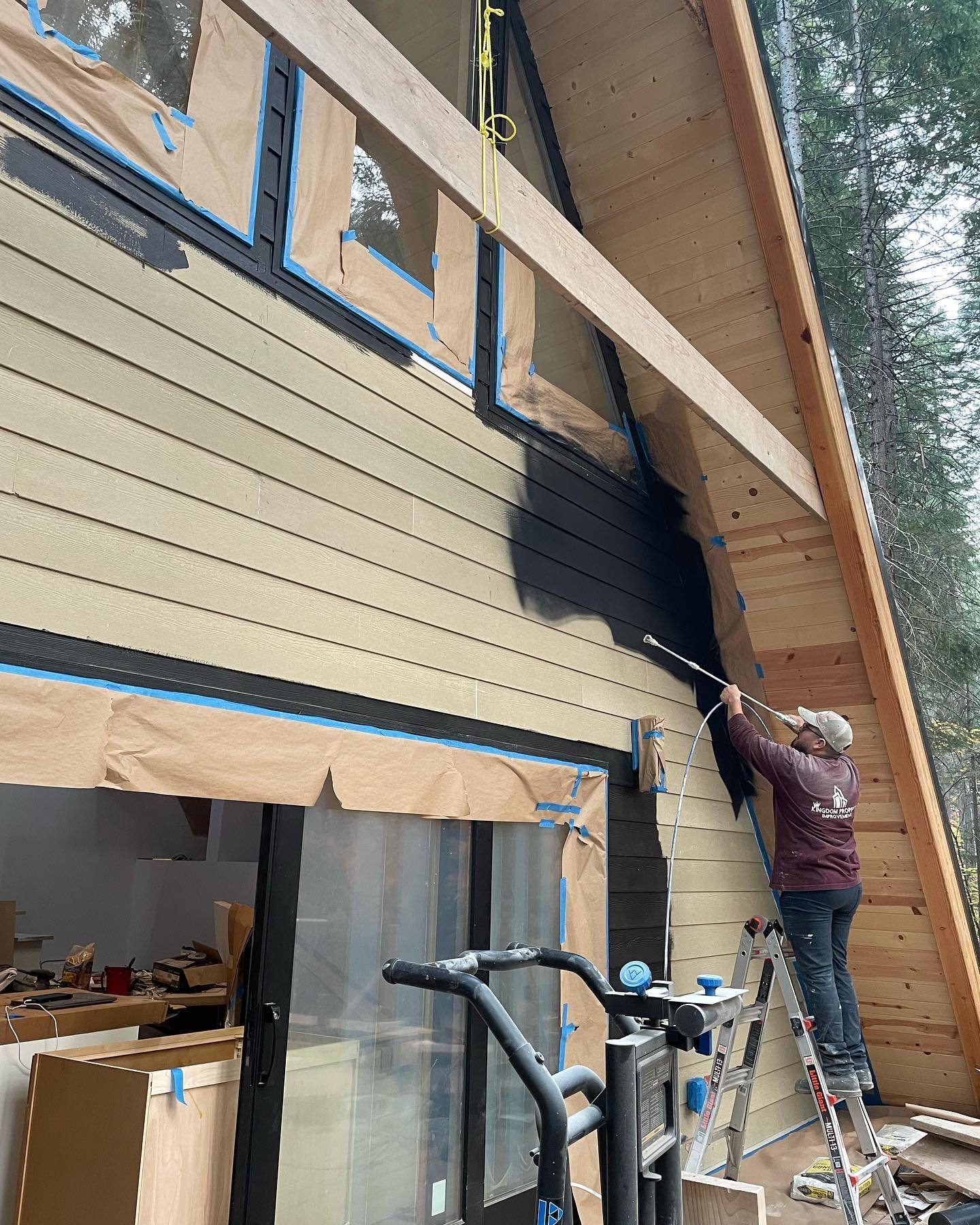Close-up of dark paint being rolled onto cabin siding