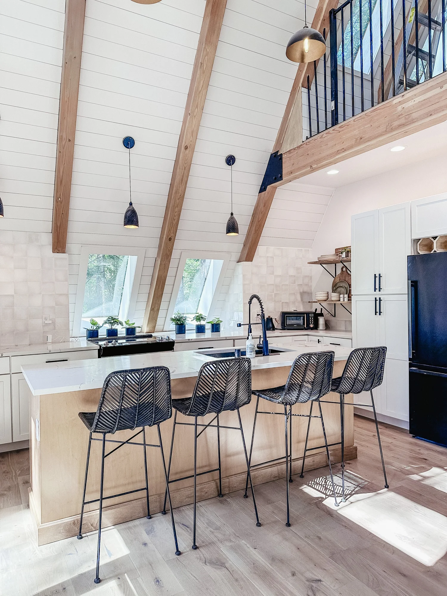 Modern kitchen with white cabinets, island seating and vaulted beams