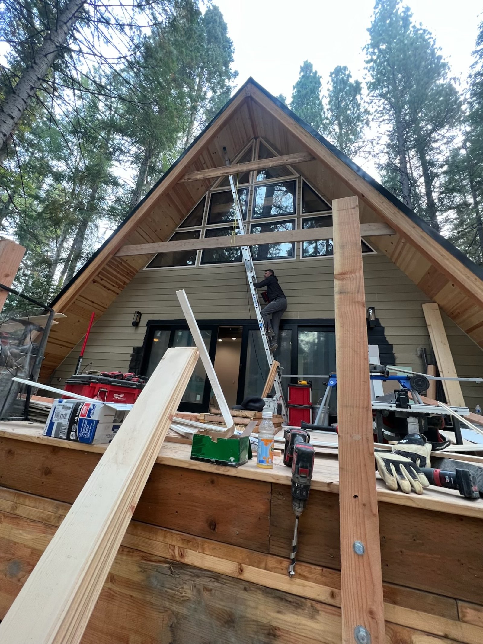A-frame house under construction with a worker installing a modern window
