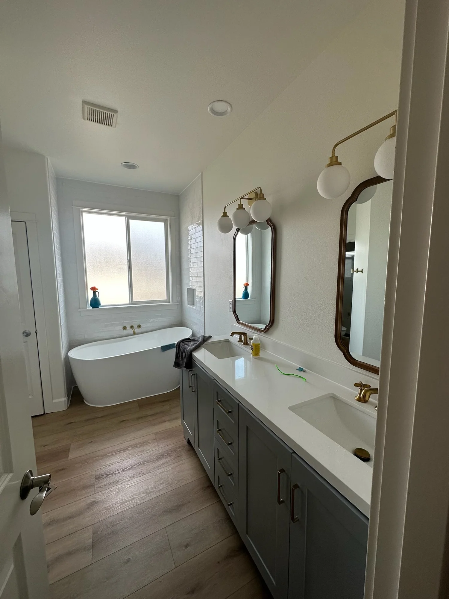 Bathroom with double sinks, mirrors and a window above the tub