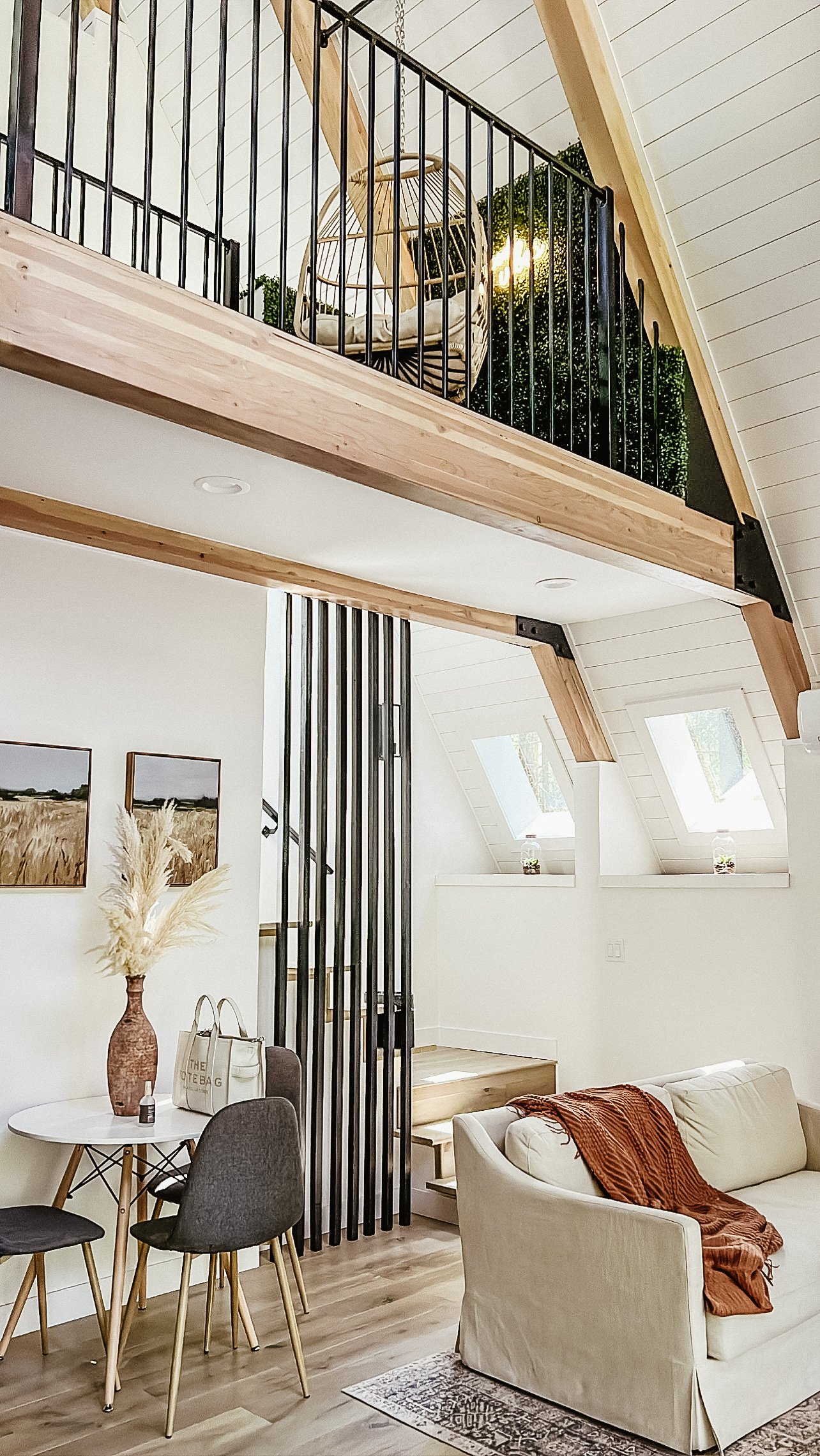 Living room with beige sofa, dining table and a loft balcony above