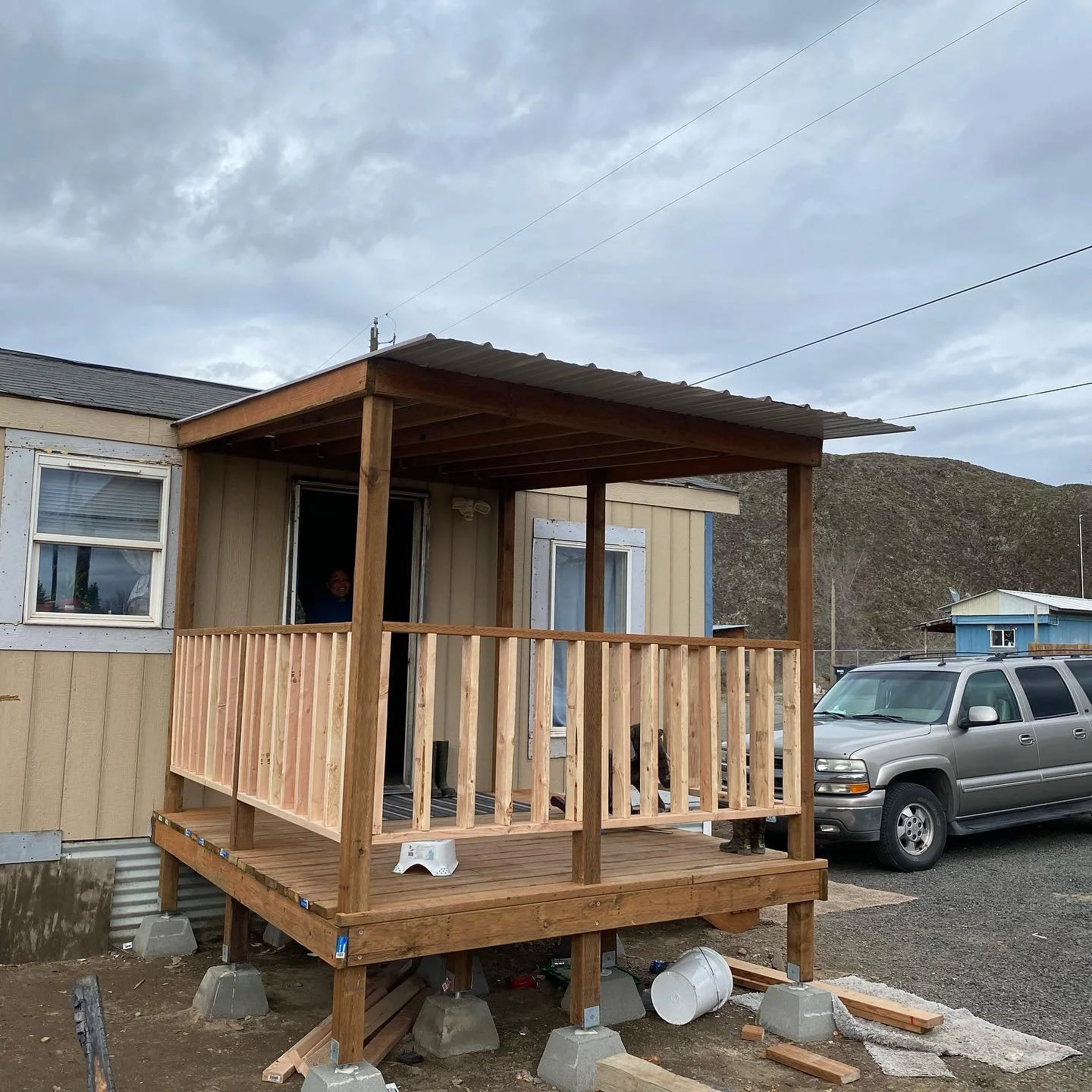Newly built wooden porch with roof and railing attached to a home
